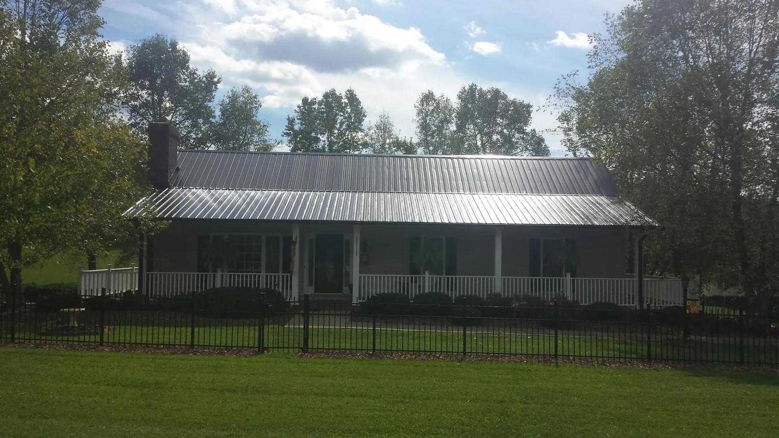 Gray metal roof on a brick ranch with a full width front porch — Gutter Guard Installation work by our crew in Sparta